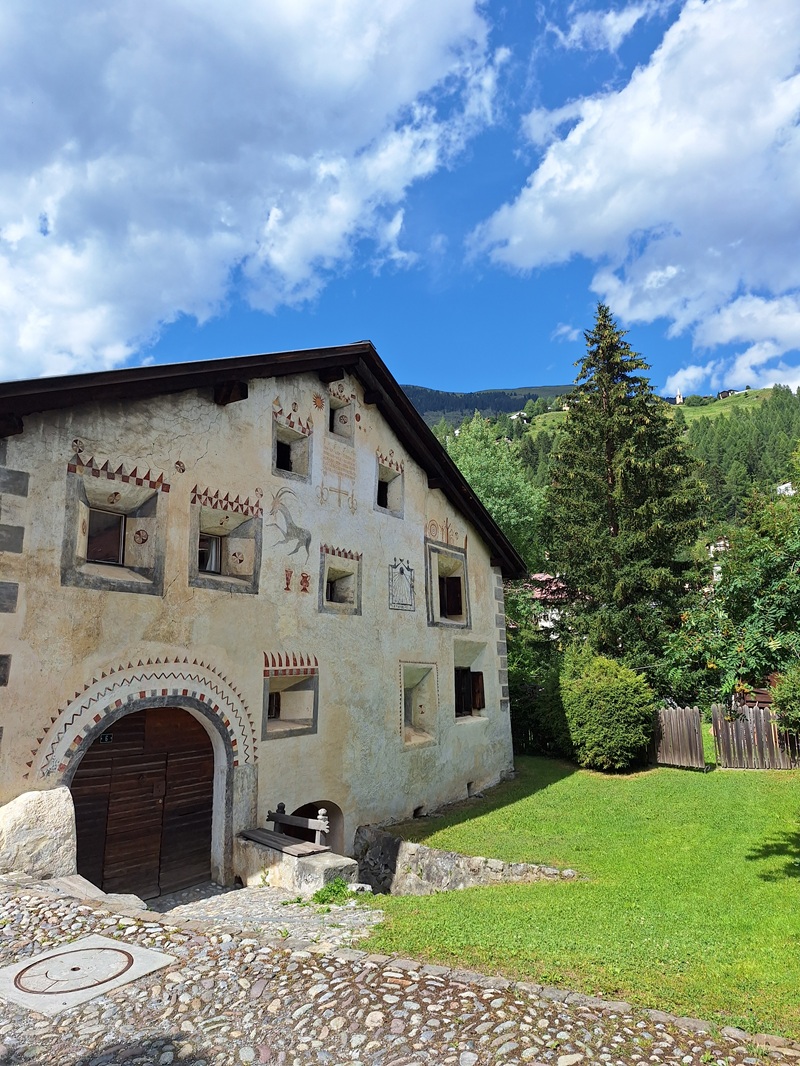 Parc Ela/Bergün: Das Ortsbild ist geprägt von vielen alte Häuser im Engadiner Stil mit den so typischen Fassadenmalereien und Sgraffiti, Erkern und Fenstergittern – und hoch oben sieht man immer den Weiler Latsch.